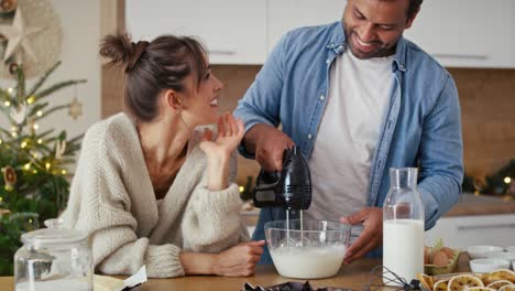 una pareja multiétnica haciendo un pastel en navidad.