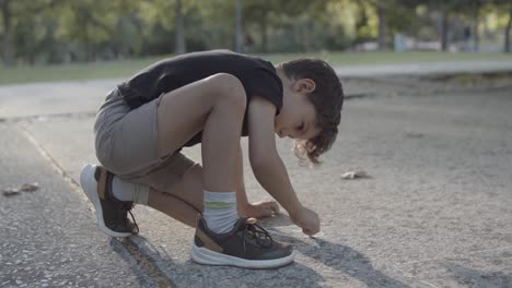 concentrated caucasian boy drawing a heart with chalk on asphalt