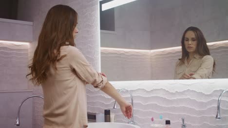 mujer de negocios poniendo camisa en el baño. mujer de cabello largo usando zapatos cerrados.
