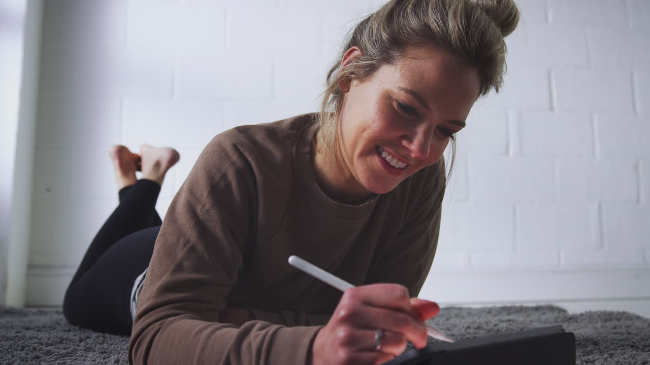 primer plano de una mujer dibujando en una tableta digital usando un lápiz óptico por la noche