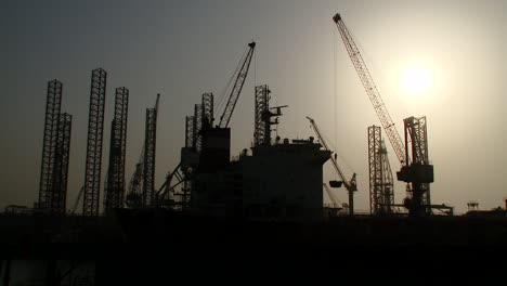 moving shot from a boat of oil rigs close to port and dry dock awaiting repairs and re-deployment at sea in bahrain in the arabian gulf.