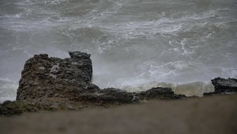 big waves hitting the abandoned concrete coast defense building ruins in stormy weather in slow motion