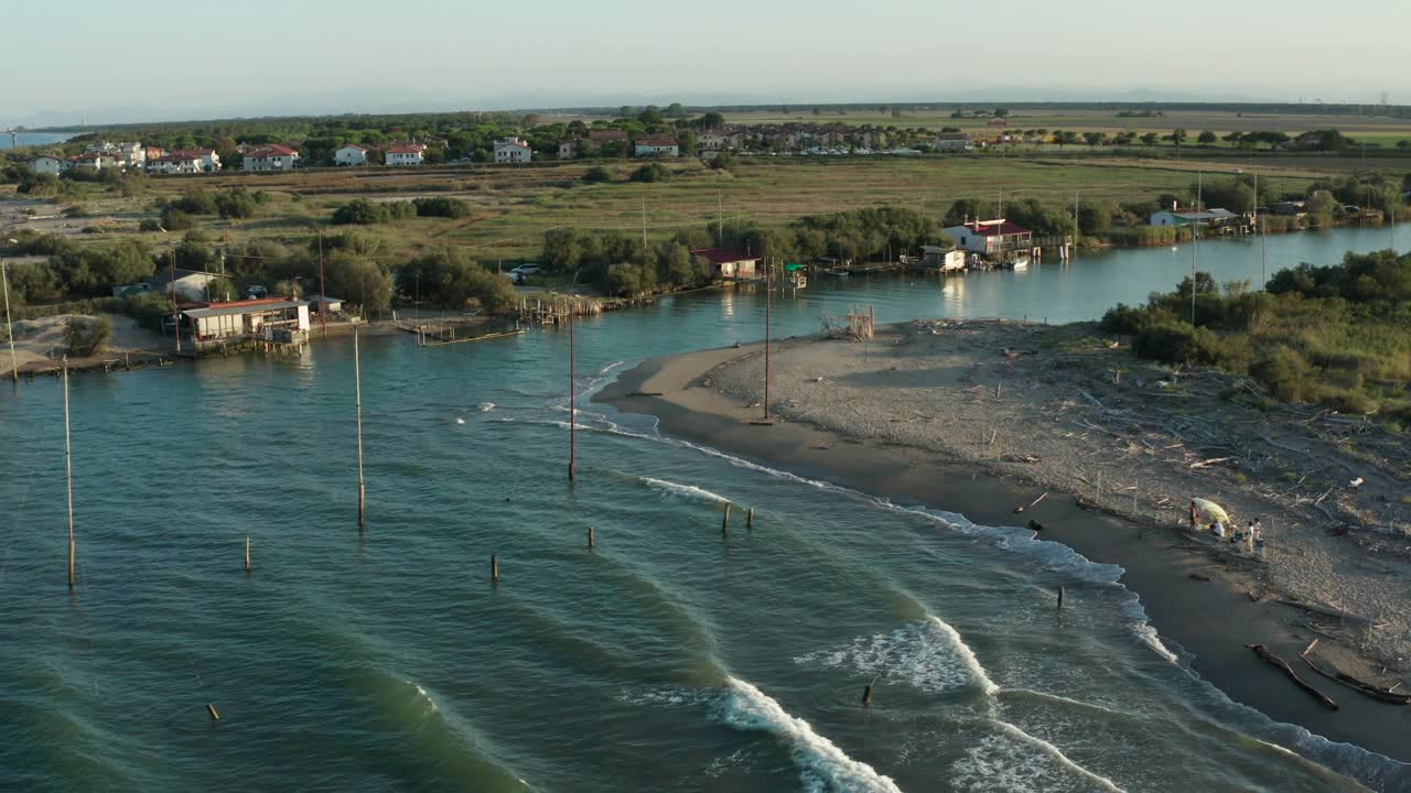 toma aérea de los valles cerca de ravenna donde el río desemboca en el mar con las típicas cabañas de pescadores al atardecer