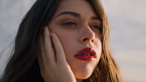 Closeup-beautiful-woman-face-with-red-lips-amazing-dark-eyes-in-front-cloudy-sky