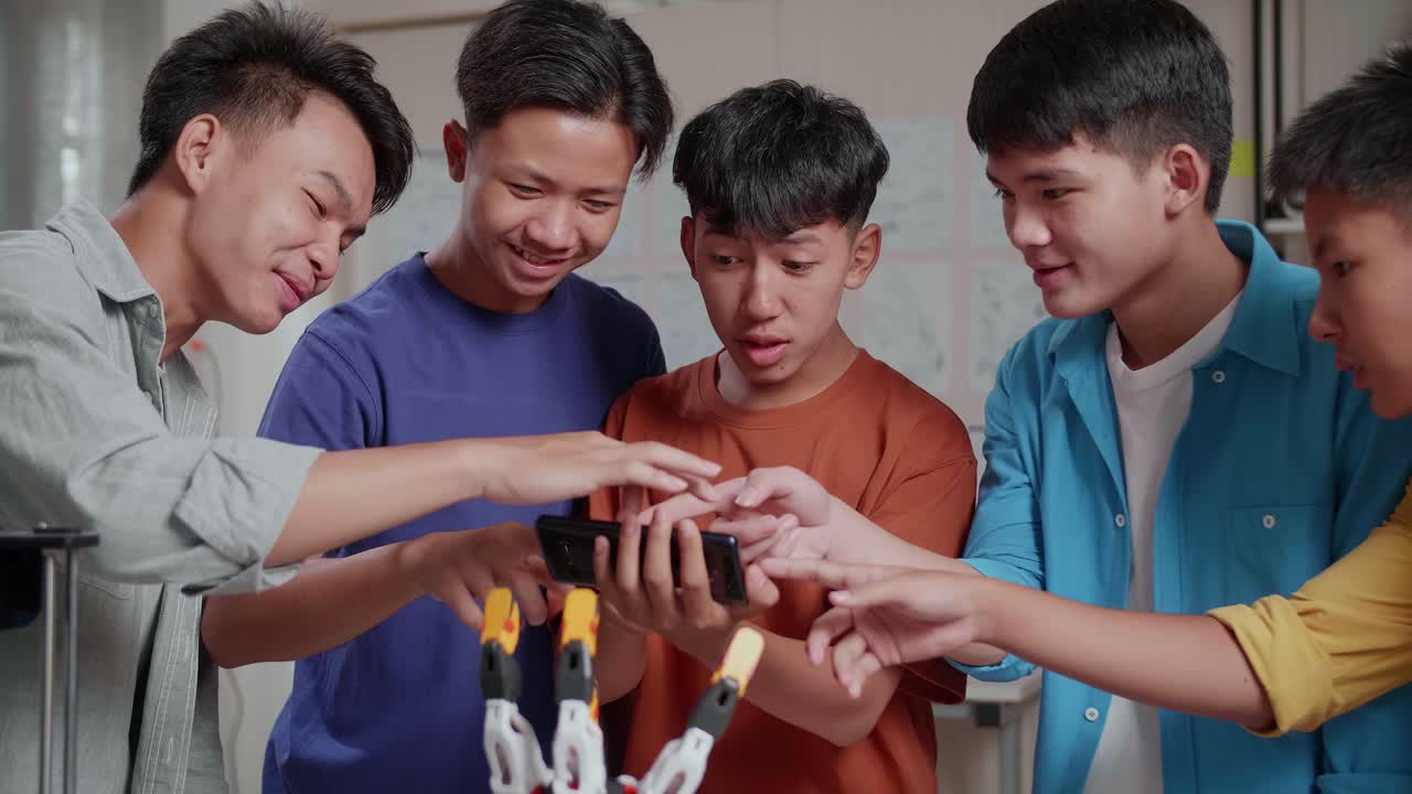 노트북과 3d 프린팅을 가진 젊은 아시아 소년 그룹이 집에서 일하는 동안 스마트 폰의 사진과 사이보그 손을 비교합니다.