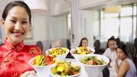 Smiling-waitress-presenting-tray-with-bowls-of-vegetables