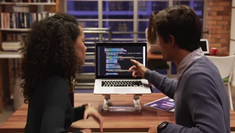 hombre de negocios creativo y mujer de negocios discutiendo sobre una computadora portátil en una oficina moderna