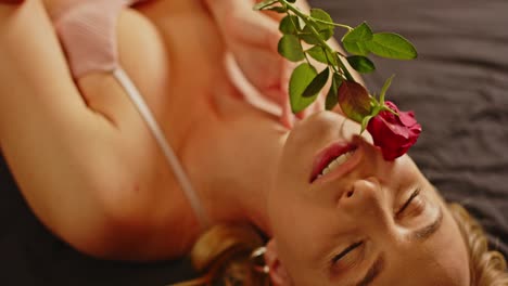 close up of a sensual woman dressed in sexy lingerie caressing her beautiful face with a rose