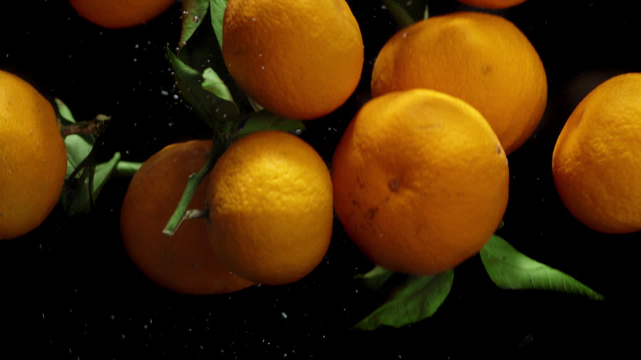 Whole mandarins falling under water with air bubbles.
