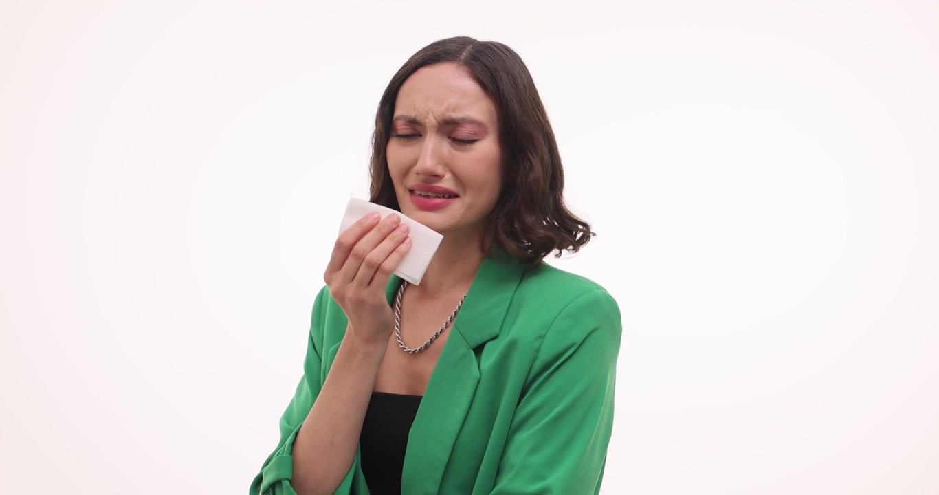 Donna triste piange e si asciuga le lacrime dagli occhi con un fazzoletto di carta.