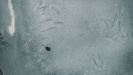 Drone-looking-down-towards-a-single-player-playing-ice-hockey-on-a-frozen-pond-or-lake-in-Canada