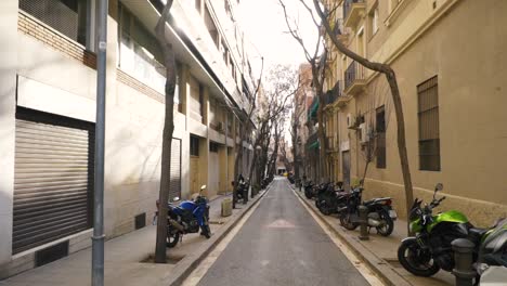 narrow city street with parked motor scooters in barcelona