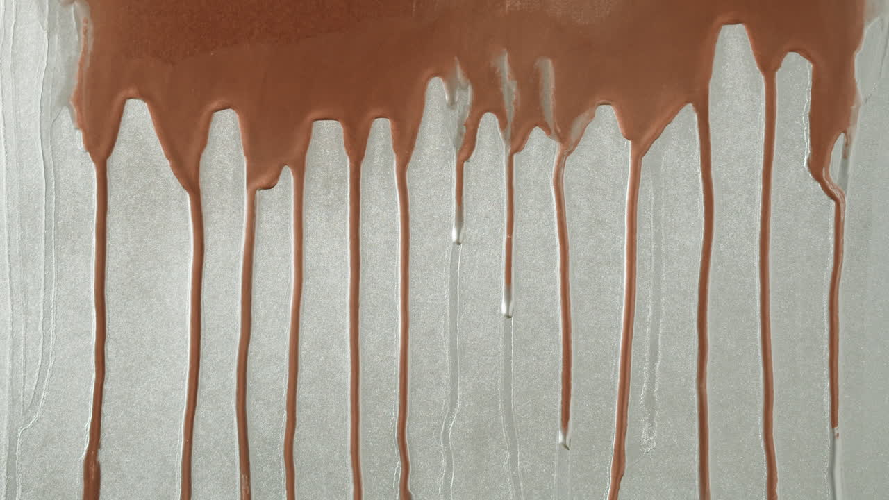 Liquido marrone viscoso che gocciola su una superficie ruvida