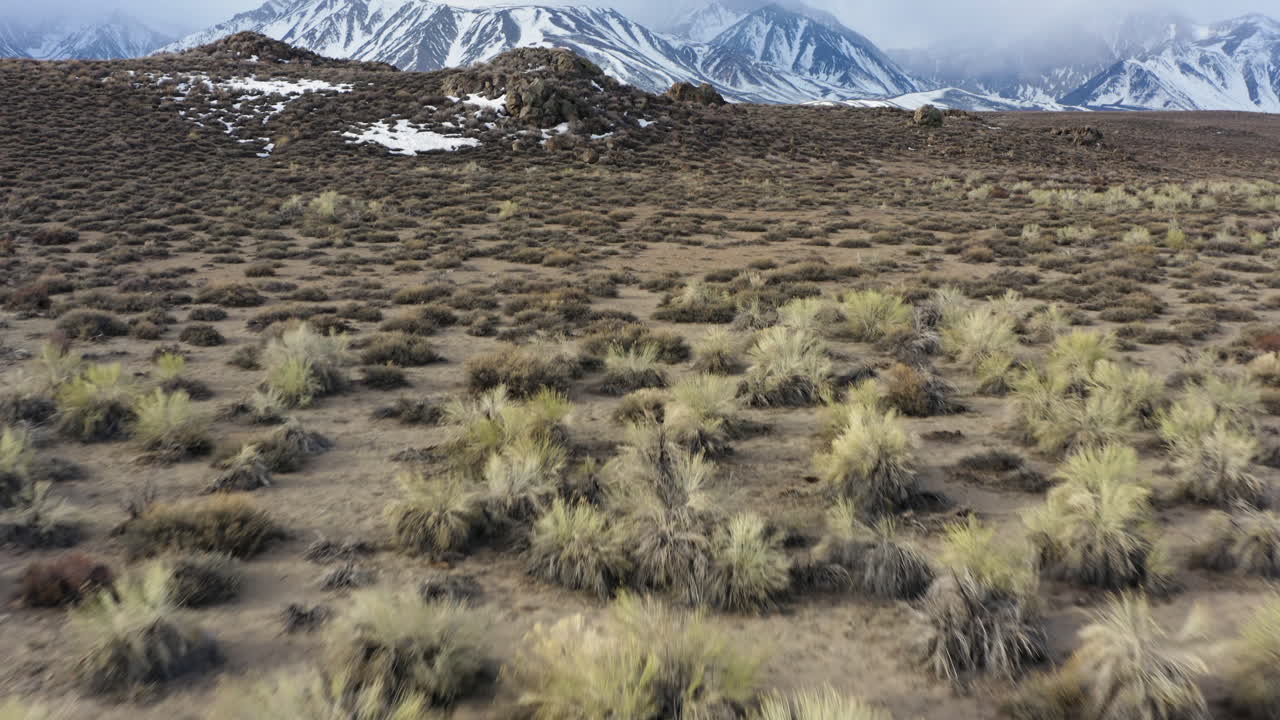 escena de vuelo hacia adelante que revela el paisaje natural de la cadena montañosa de sierra nevada oriental en california, contraste entre el desierto árido y el paisaje montañoso invernal