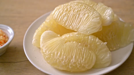 pomelo fresco pelado, pomelo o shaddock en plato blanco