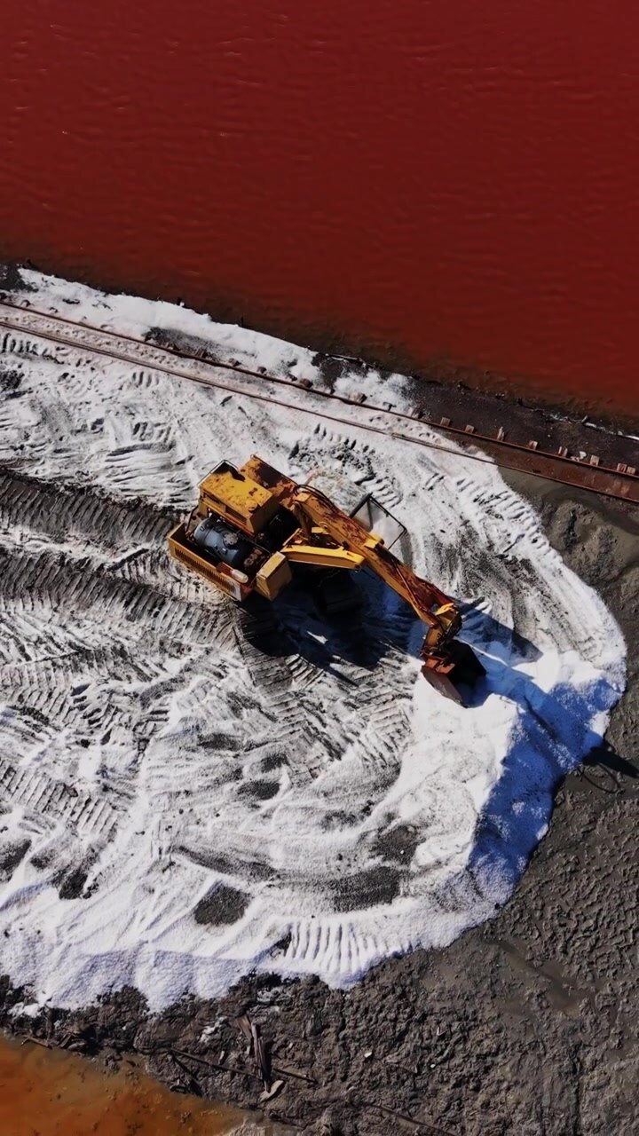Attività in una miniera di sale con macchinari che spostano minerali vicino all'acqua.