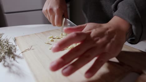 Hände-Schneiden-Knoblauch-Mit-Einem-Messer-In-Kleine-Stücke---Nahaufnahme