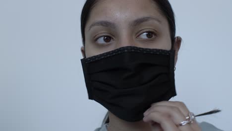 uk asian female teenager putting on black cotton face mask