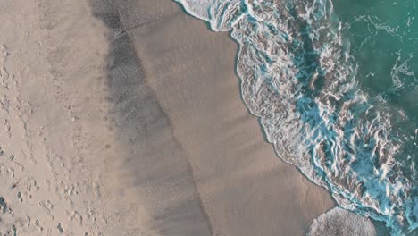 ocean waves splashing on sandy shore of bovaer beach in norway - aerial top down