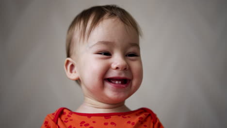 happy cute little toddler laughing cheerfully with toothless smile. adorable baby portrait smiling and showing two lower teeth. close up.