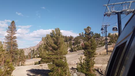 tiro estático de cardán desde la góndola mirando hacia atrás a la montaña mientras pasa sobre la línea de árboles en la montaña mammoth en california durante el verano