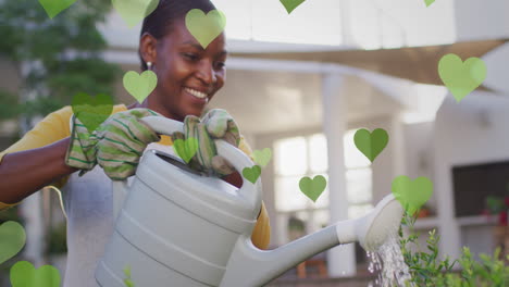 animation of green hearts over happy african american woman watering plants