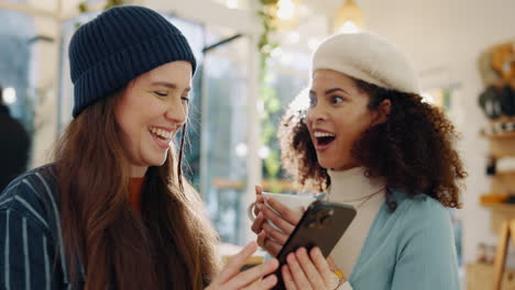 two friends laughing at phone in cafe