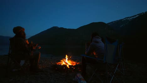 group of hikers sitting near campfire 4k