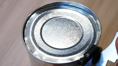 an opening a tin can with a can opener close-up