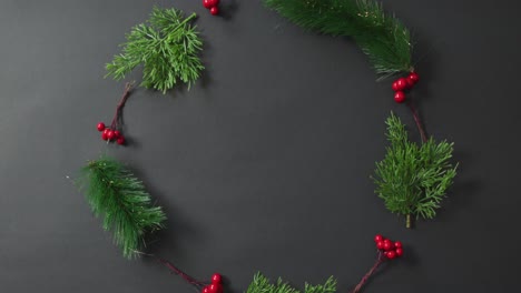 Video-of-christmas-decoration-sprigs-with-red-berries-and-copy-space-on-black-background