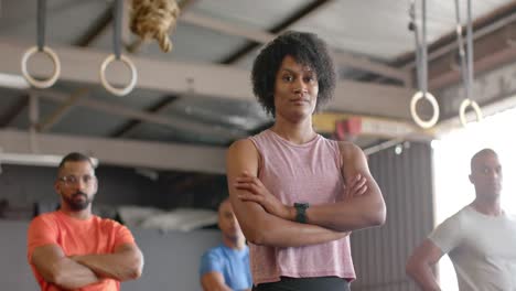 portrait of diverse group of men and women standing and crossing arms at gym in slow motion