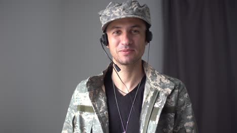 cinematic shot of young happy smiling male soldier in camouflage military uniform is making technology video call to her family or friends just turn back home after mission.