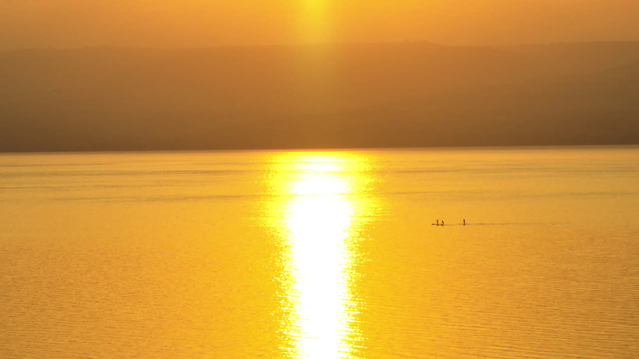 백그라운드에서 산과 함께 일출 동안 바다에서 친구 패들 보드