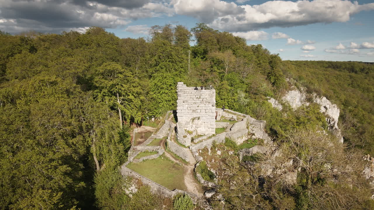 Dinamica orbita in 4K UHD di un drone intorno alle rovine del castello di Hohengundelfingen, sopra la valle del Lauter, che rivela le dolci colline del Giura Svevo, le foreste e i cieli azzurri.