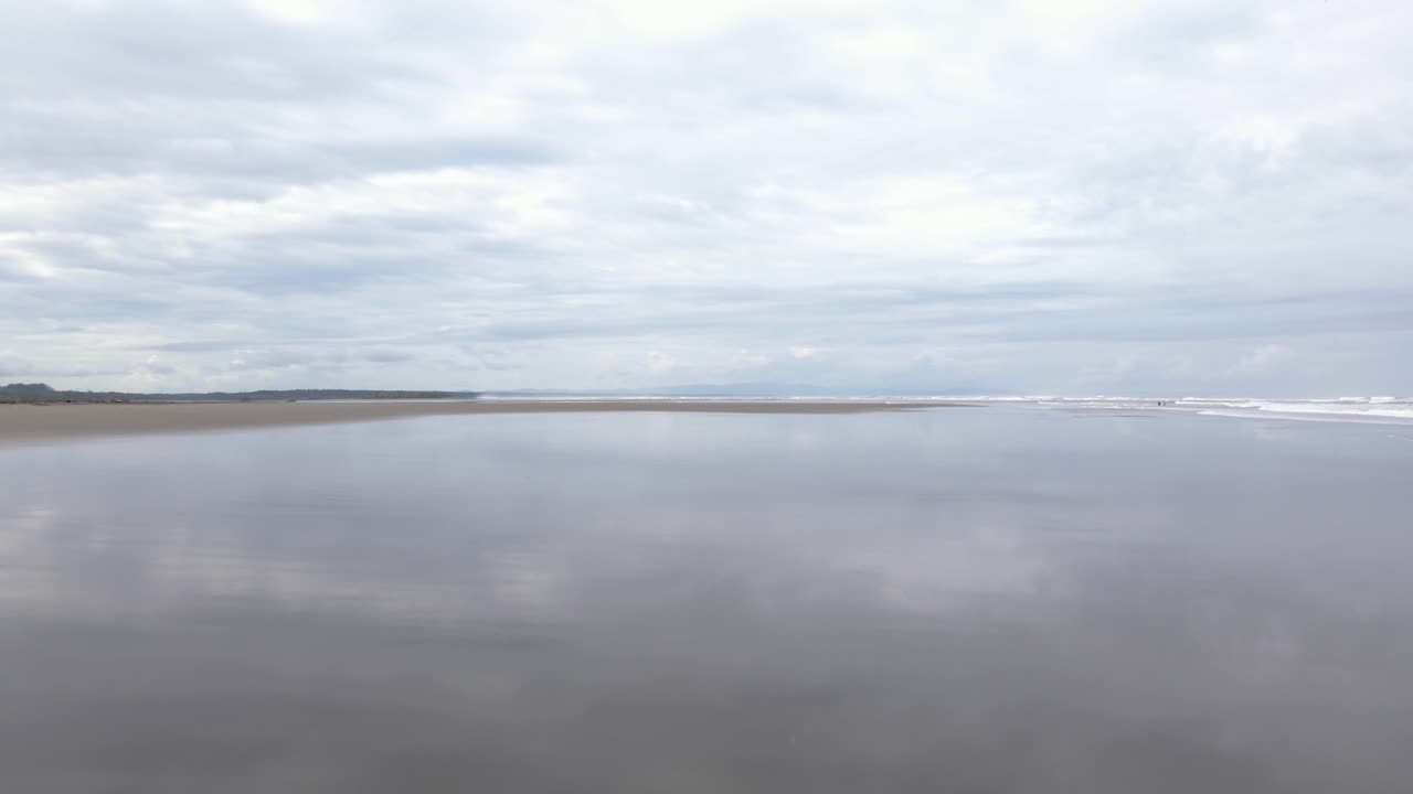 vuelo aéreo justo encima de la playa y reflejo del cielo