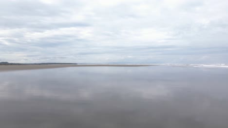 aerial flight right above beach and reflection of sky