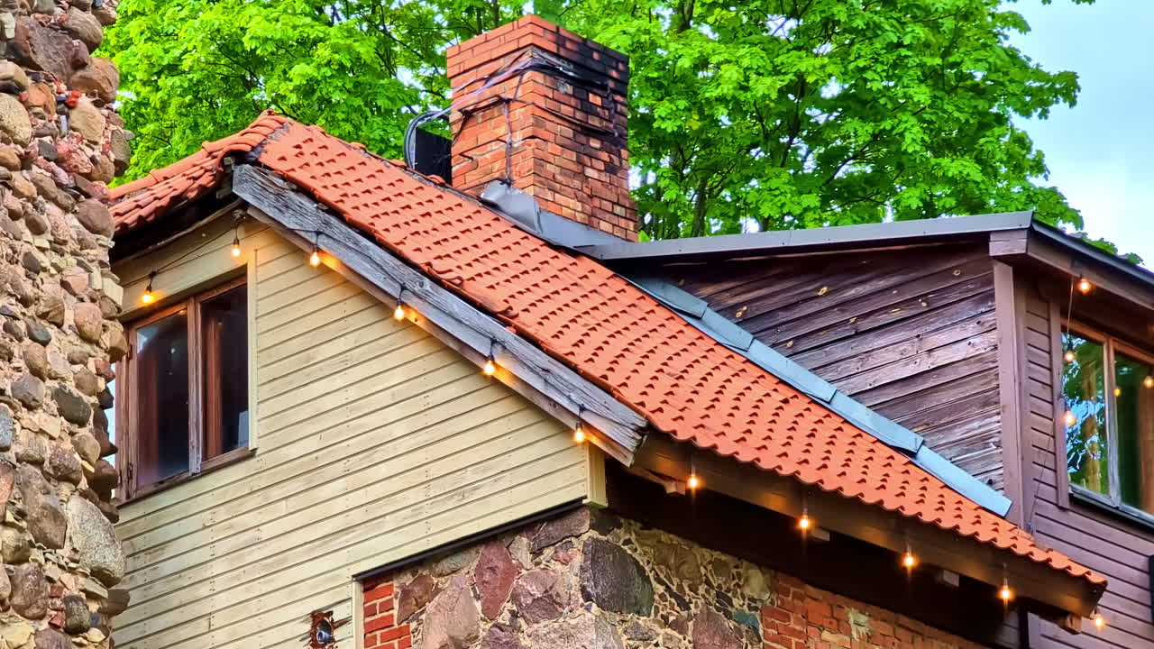 Stone building with red tiled roof and brick chimney in closeup