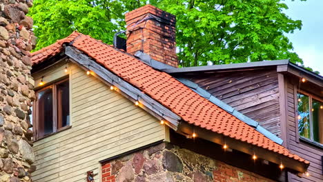 Stone building with red tiled roof and brick chimney in closeup