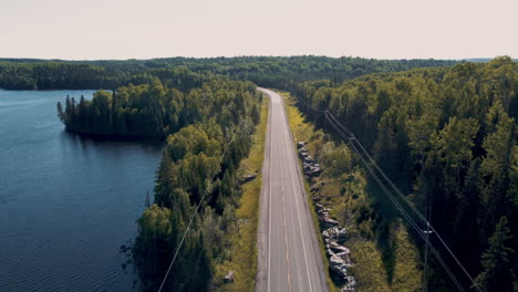 scenic aerial view of a road through a forest and lake