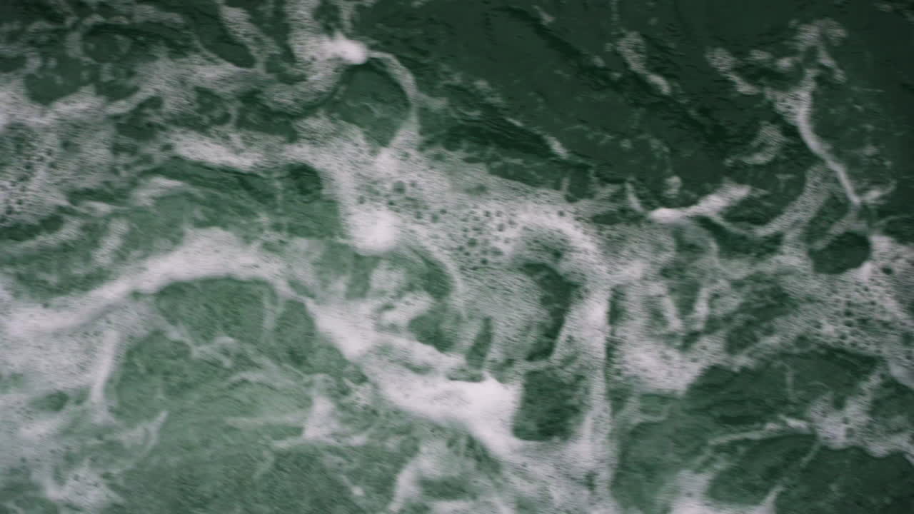 Slow-motion low shot above fresh broken waves creating bubbles on the surface