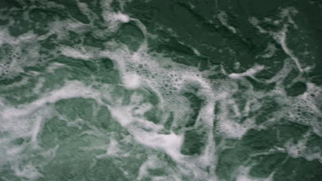 slow-motion low shot above fresh broken waves creating bubbles on the surface