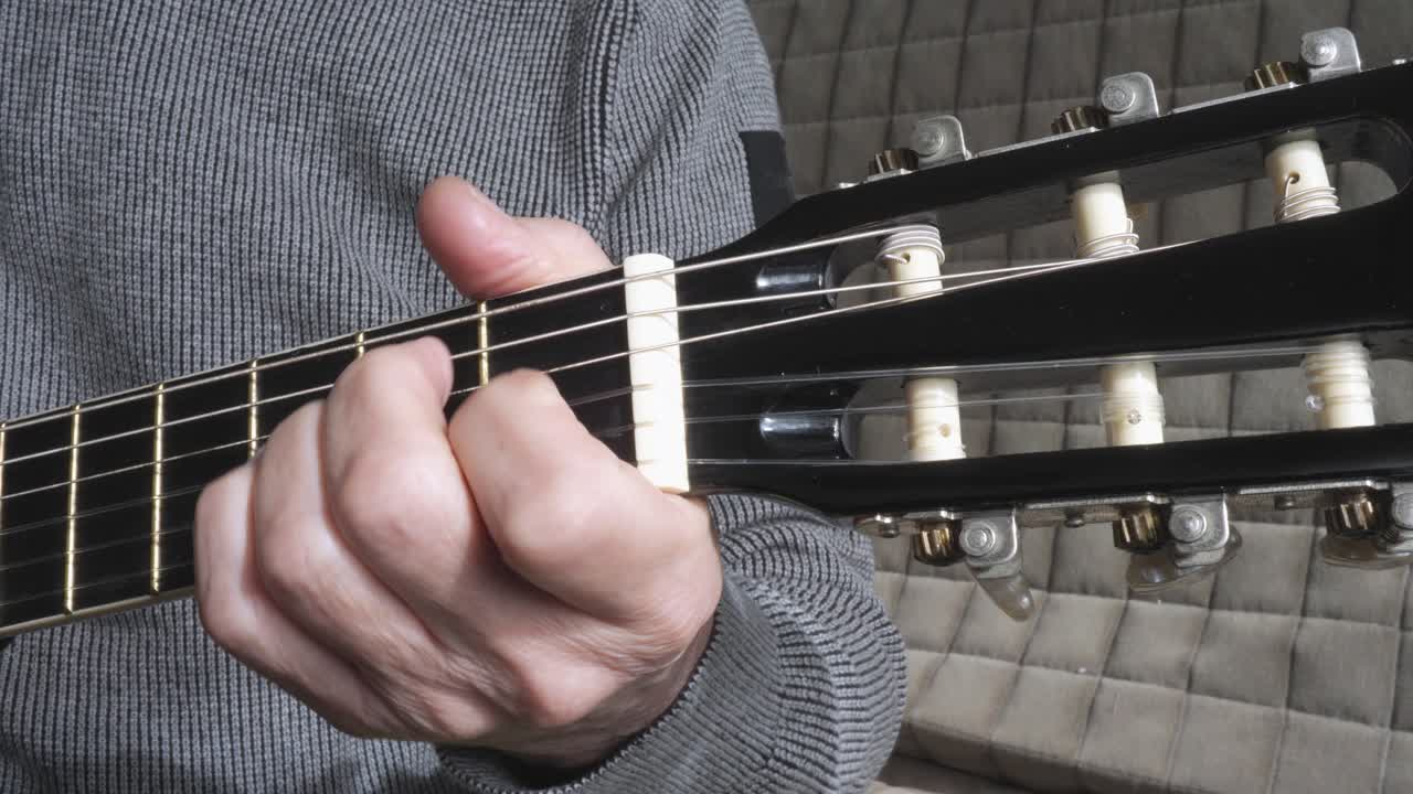 Man checking strings of acoustic guitar close-up