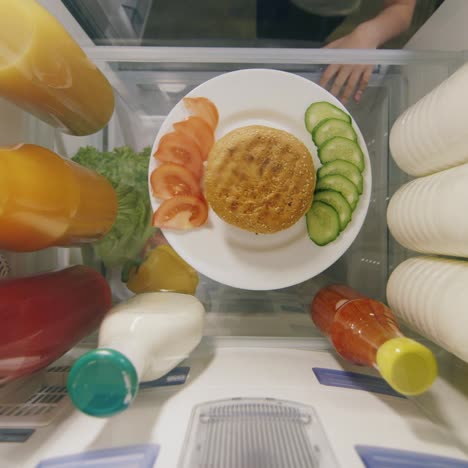 la mano de un hombre toma una hamburguesa y una salsa del refrigerador 1