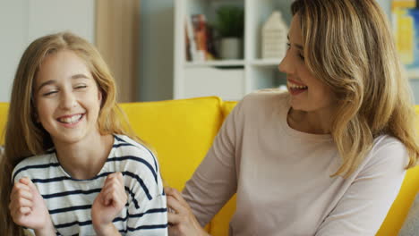 Cute-Blonde-Daughter-With-Her-Mother-Who-Tickling-Her-In-The-Living-Room