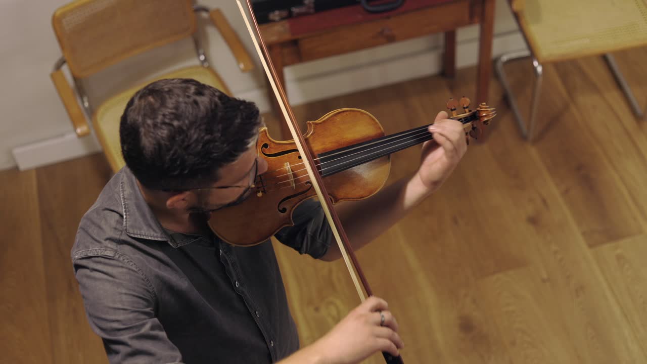 un luthier barbudo adulto tocando un violín hecho a mano