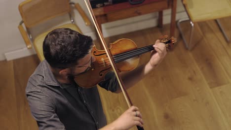un luthier barbudo adulto tocando un violín hecho a mano