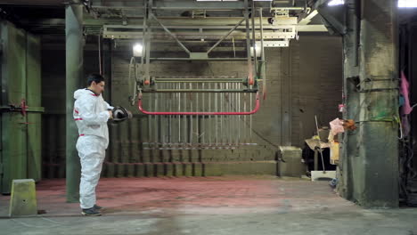 technician starts his work inside the workshop. worker in white protective suit putting on respirator on his head before the painting procedure.