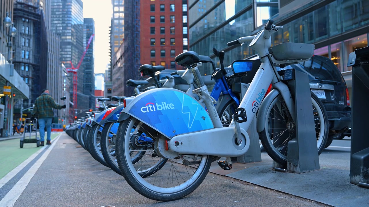 New York, USA, 15. april 2026: Elektrisk Citi Bike ved ladestasjon i New York City. Blå elektrisk leiesykkel parkert ved en stasjon i en gate på Manhattan med skyskrapere i bakgrunnen.