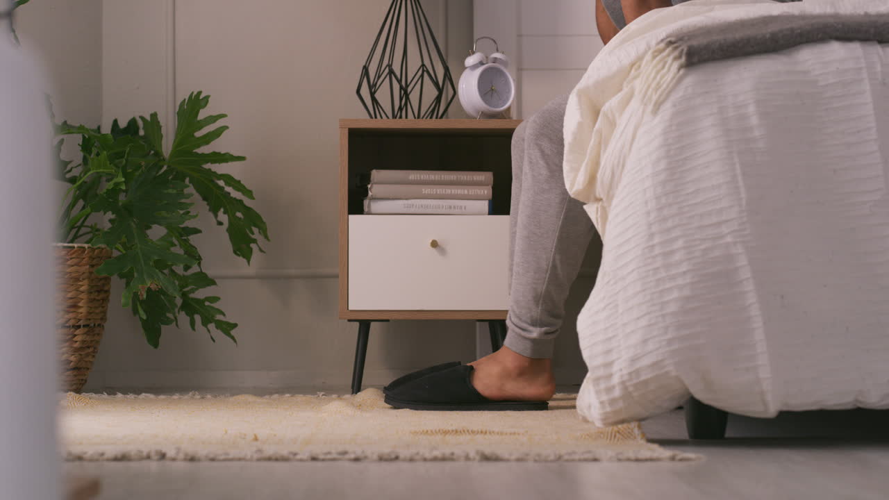 Bedroom scene with person putting on slippers
