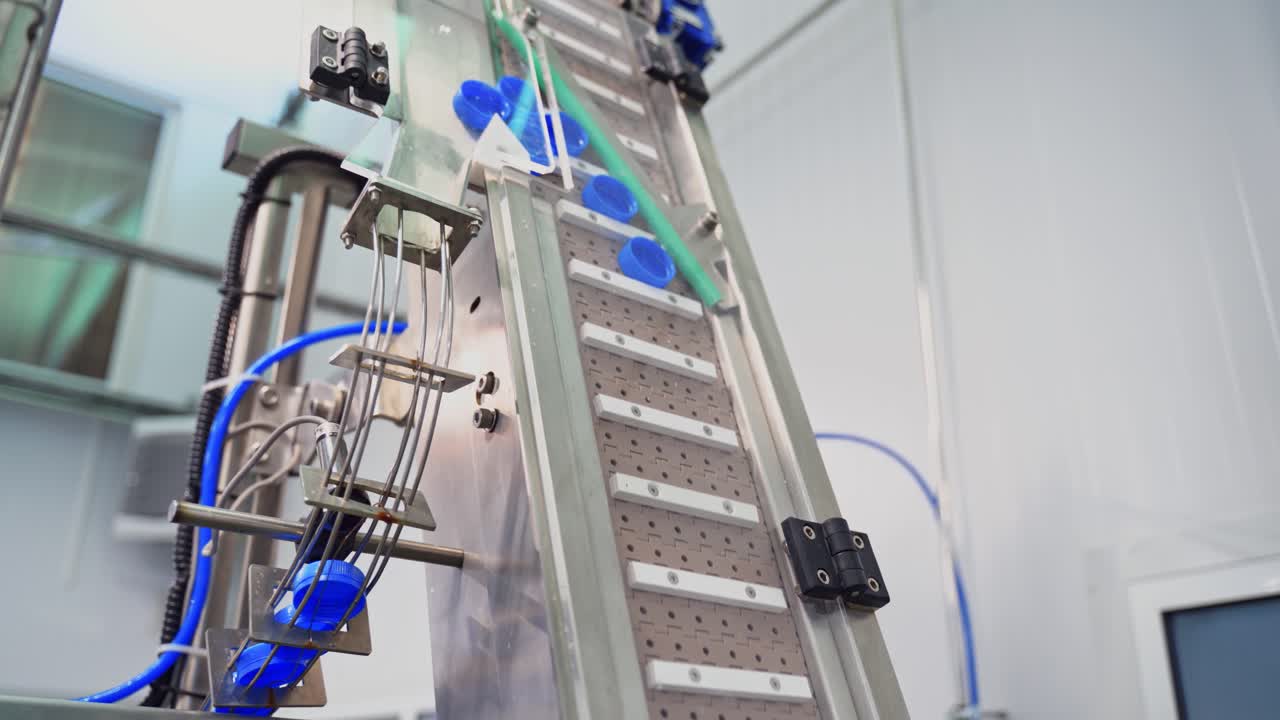 Automatic technology in a dairy factory. Modernized equipment in a plant. Conveyor line rising up with plastic lids for further packaging. Slow motion.